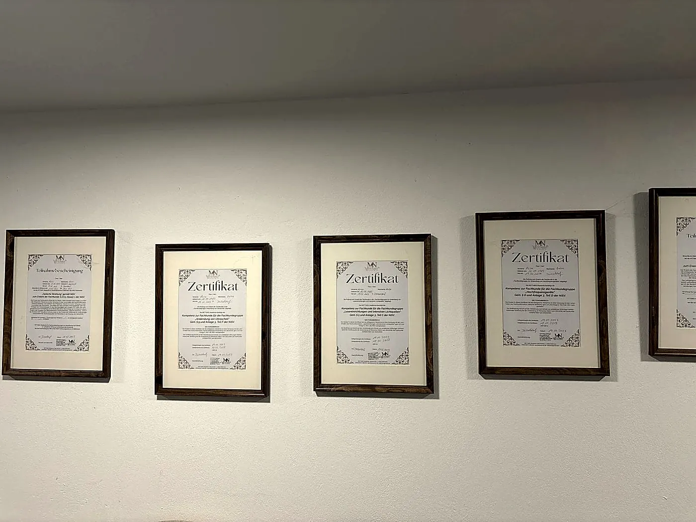 Gerahmte Zertifikate der Fachkunde nach NiSV an der Wand
